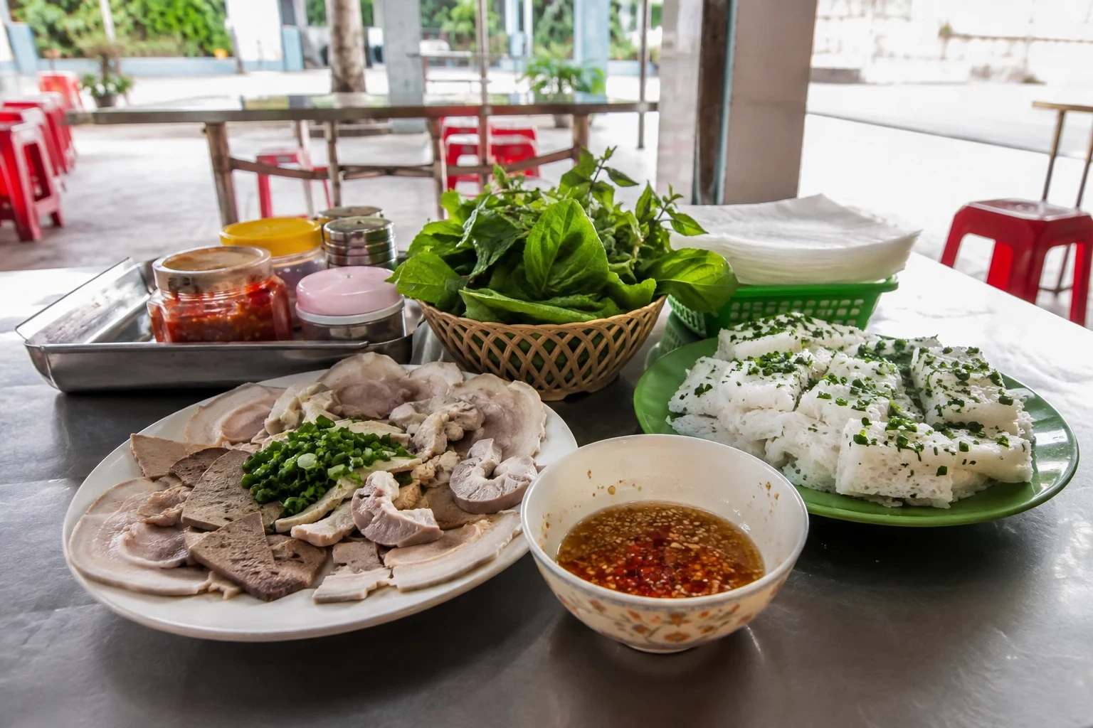 Mâm bánh hỏi, thịt luộc, lòng, rau xanh và nước chấm trên bàn inox